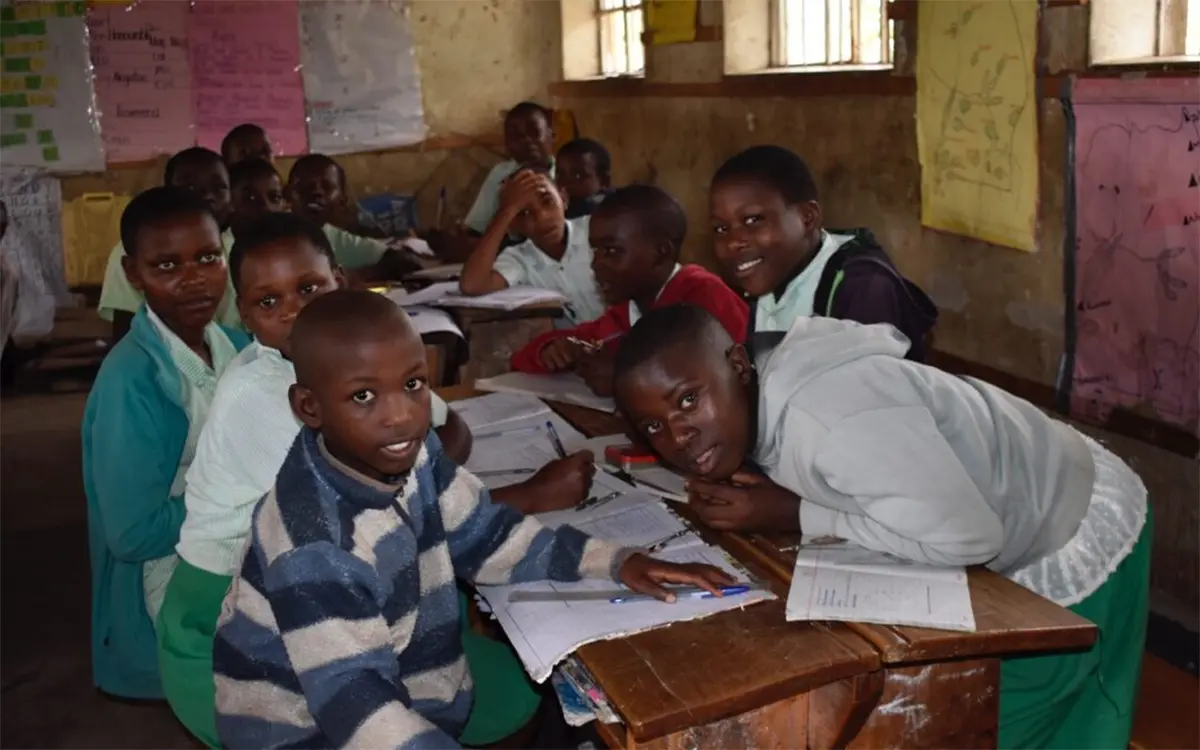 Children smiling around a table with papers in front of them